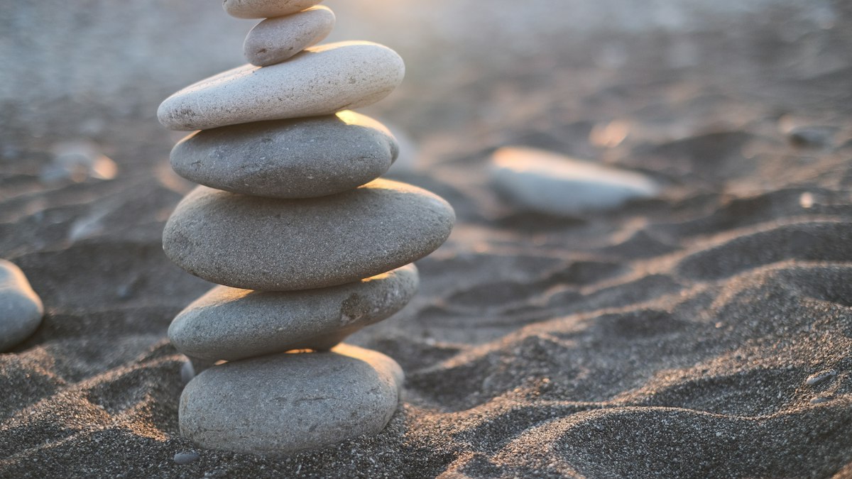 A stack of smooth stones balanced on a sandy beach